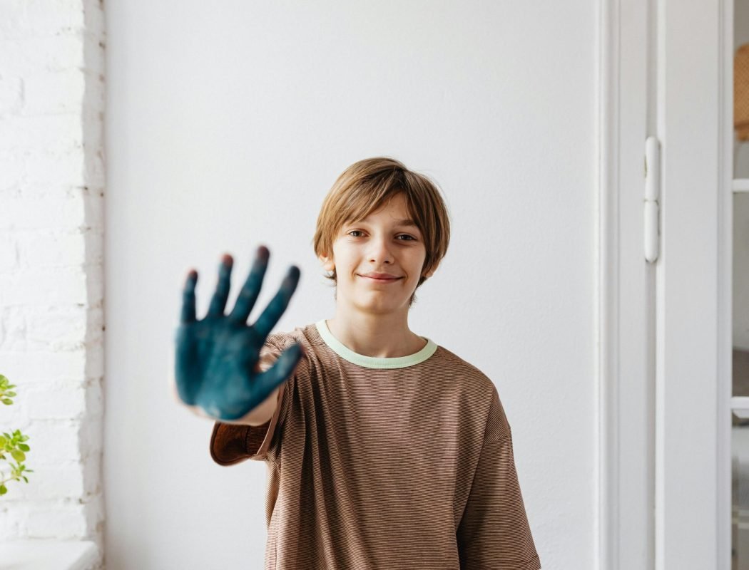 pexels-photo-7692762-7692762 A Boy in Brown Shirt Smiling while Showing His Hand with Paint